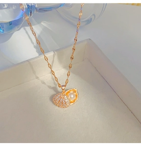 Detailed view of an openable rose gold shell necklace with a pearl and zircon inlay