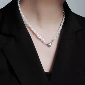 Gros plan d'un collier de perles avec pendentif cœur mosaïque sur une veste noire