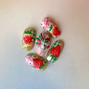 Faux ongles 3D fraise avec nœuds vichy rouges et accents métalliques dorés