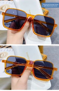 Detail view of square orange semi-rimless sunglasses with dark gray lenses in hand