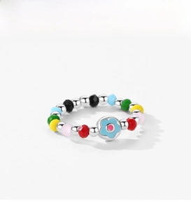 Dettaglio dell'anello di perline colorate in argento S925 con fiore blu su bianco