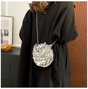 Detail view of a silver metal rose evening bag with a delicate chain strap on model
