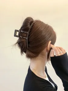 Detail view of large dark brown shark hair claw clip securing a thick bun hairstyle