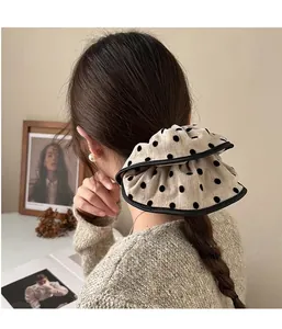Detail of oversized polka dot scrunchie with ruffled edges on a beige fabric background