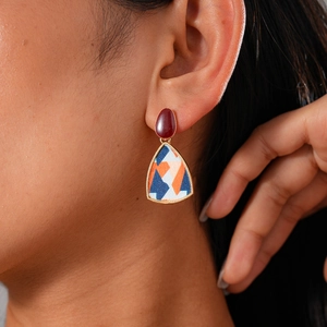 Detail of geometric resin pearl flower earrings with burgundy studs and patterned pendant