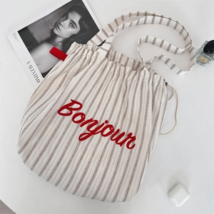 Detail of striped canvas tote bag with red Bonjour embroidery and drawstring closure
