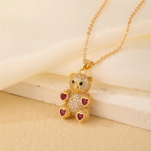 Detail of gold bear pendant necklace with micro-set diamonds and red heart stones