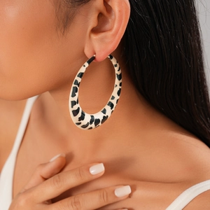 Close-up of a large round earring with black and white animal print on female model