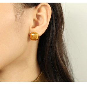 Boucles d'oreilles carrées en acier titane doré avec nacre portées par un mannequin