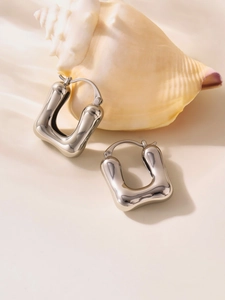 Detailed view of silver U-shaped geometric earrings on a seashell decorative background