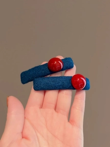Close-up of contrast color felt hair clips in deep blue with vibrant red bead accents