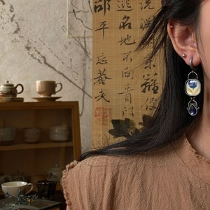 Ancient Egyptian enamel flower asymmetric earrings with blue crystal drops on model