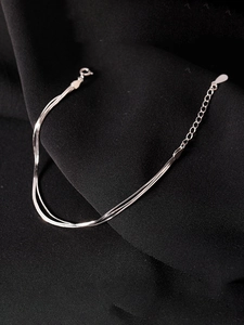 Detailed macro view of layered silver snake chain bracelet with secure lobster clasp