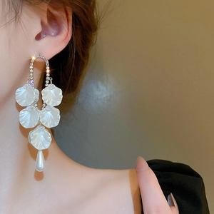 Détail de boucles d'oreilles fleur de perle avec pétales de nacre et strass brillants