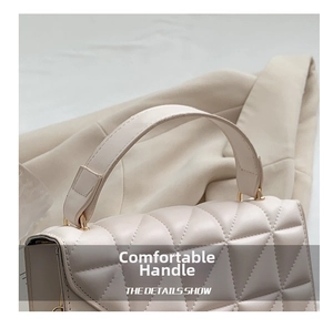 Détail du sac matelassé crème avec poignées renforcées et finitions métalliques dorées