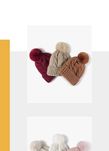 Dettaglio di cappelli invernali multicolore in maglia a trecce con grandi pompon in pelliccia