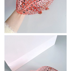 Detail of pink lip-shaped clutch bag featuring sparkling rhinestones and a hard shell