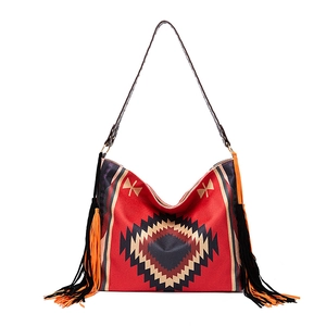 Close-up of bohemian red woven bag showing geometric tribal patterns and tassel details