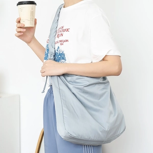 Minimalist light blue drawstring canvas shoulder bag shown worn by a model in casual style