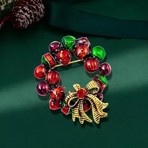 Detail of Christmas wreath brooch with red green enamel and gold bow on green silk