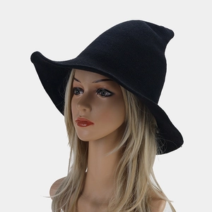 Front view of a black knitted pointed wizard hat with wavy brim on a female model