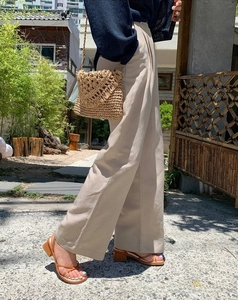 Detail of hand-woven straw crossbody bag with V-shaped texture in natural light