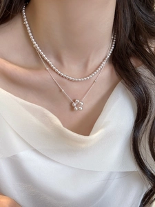 Détail d'un collier double rang en perles avec pendentif fleur sur le cou d'un modèle