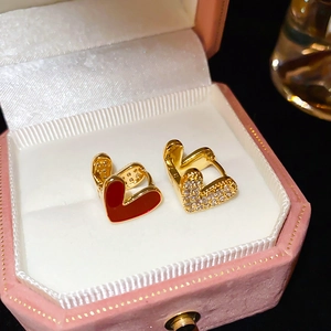 Détail de boucles d'oreilles cœur en plaqué or avec émail rouge et pierres en coffret