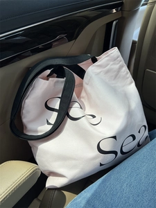 Detail of canvas tote bag with Sea print and black straps placed on a car seat