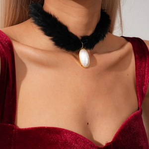 Gros plan du ras-du-cou en fausse fourrure noire avec pendentif perle ovale