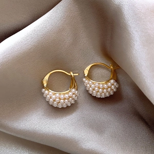 Elegant gold hoop earrings with triple rows of white pearls on champagne silk fabric