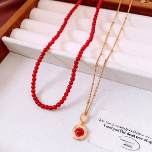 Detail of 18K gold plated tiger eye necklace with red beads and luxury round pendant