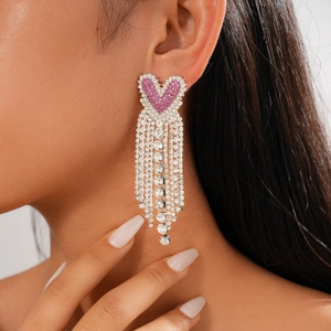 Close-up of elegant long tassel heart earrings with pink rhinestones on a model