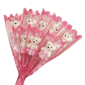 Detail view of 9 white teddy bear plush dolls in pink skirts wrapped in floral paper