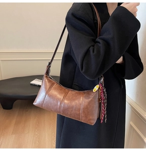 Retro brown crescent shoulder bag with stitching details and smiley tag on black coat