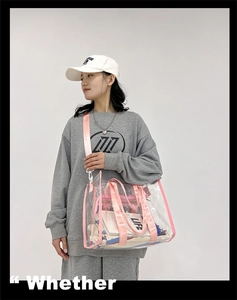 Detail view of large PVC transparent tote bag with pink straps worn by a casual model
