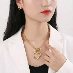 Gros plan sur l'ensemble collier et boucles d'oreilles cœur doré avec perles et cristaux