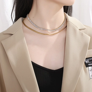 Detail of layered gold snake chain and silver crystal tennis necklace on model