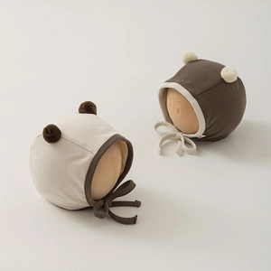 Detail of newborn baby tie-on earflaps hats with cute plush pom-poms on wooden mannequin