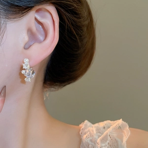 Macro shot of candy-shaped stud earring with clear crystal and white pearls on model