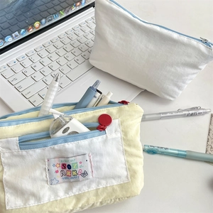 Close-up of cute multi-layer canvas pencil cases with colorful woven tags on a desk
