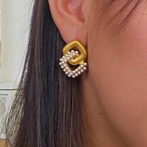 Detailed view of gold earrings with twisted metal rings and elegant inlaid pearls