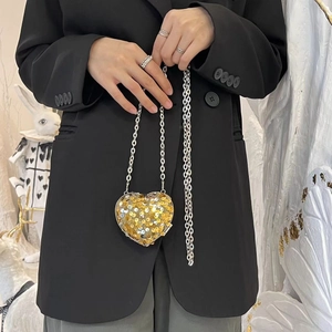 Detail of a heart-shaped evening clutch bag with sparkling gold sequins and silver chain