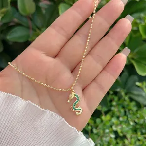 Close-up of 18K gold dragon pendant with sparkling green zircon crystals on a bead chain
