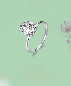 Macro detail of oval-cut zircon ring with four-prong silver setting on floral background