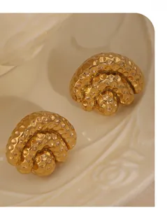 Macro view of gold plated titanium earrings with vintage hammered texture on ceramic plate