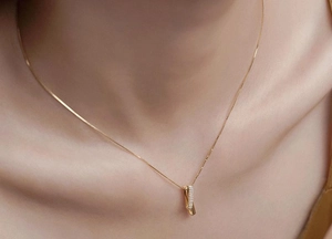 Close-up of gold geometric twisted pendant with pavé cubic zirconia on neck