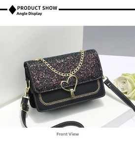 Detail view of the black sequined flap and golden heart-shaped clasp on a crossbody bag