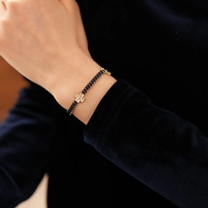 Close-up of gold clover bracelet with baguette-cut blue gemstones on velvet sleeve