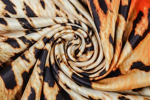 Close-up of leopard print fabric texture showing the silky sheen and drape of the material